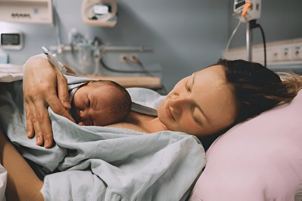 Mutter liegt mit Neugeborenem im Bett